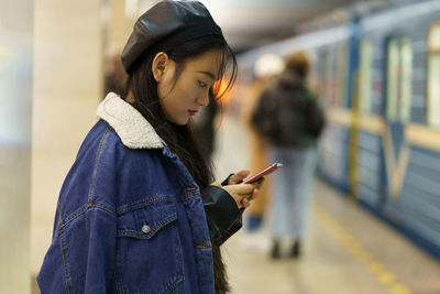 Addicted from phone chinese girl pay no attention on arriving train on platform scroll social media