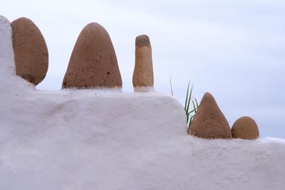 Sculptures on white wall against clear sky