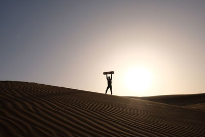 Man standing in desert against sky during sunset