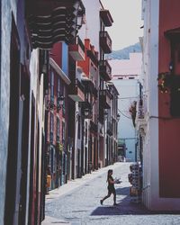 Man walking on footpath amidst buildings in city