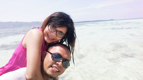 Portrait of smiling young woman wearing sunglasses at beach