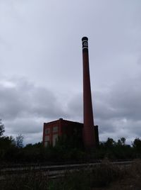 Low angle view of smoke stack on field against sky