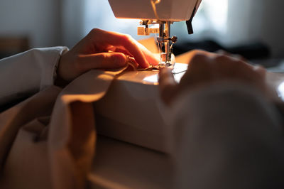 Cropped seamstress sewing in evening