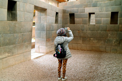 Rear view of woman photographing historic building