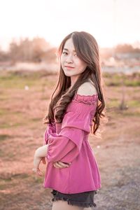 Side view of a smiling woman standing on field