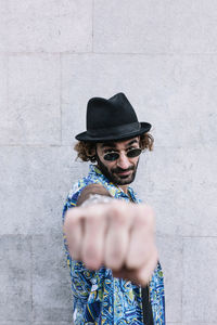 Portrait of man wearing sunglasses standing against wall