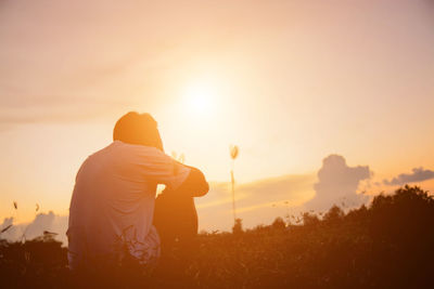 Rear view of man on field against sky during sunset