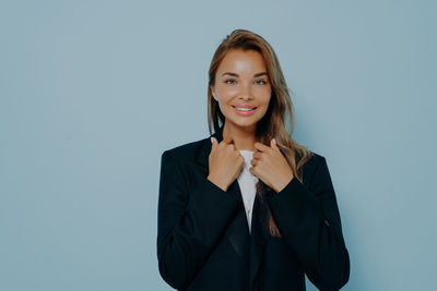 Portrait of young woman standing against white background