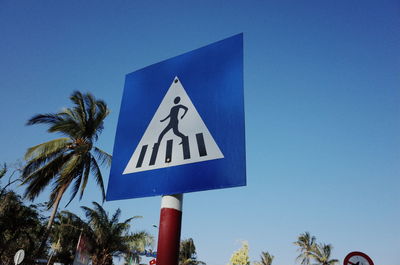 Low angle view of road sign against blue sky