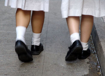 Low section of girls wearing school uniform walking on sidewalk