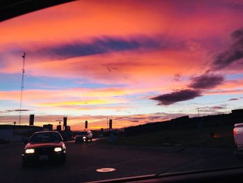 Cars on street against orange sky