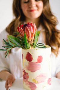 Young woman with birthday cake, close up. the cake is decorated with protea flowers.