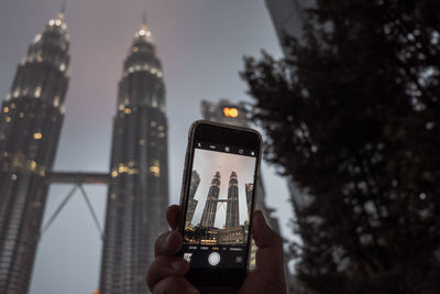 Low angle view of person using mobile phone in city