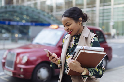 Uk, london, happy businesswoman looking at cell phone