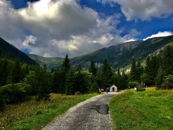 Road amidst trees and mountains against sky