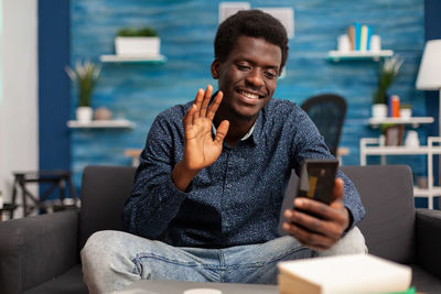 Smiling young using phone while sitting at home