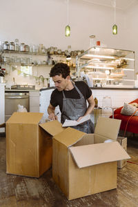 Male owner checking inventory in cardboard boxes at cafe