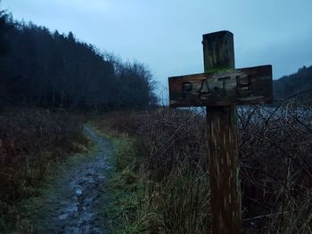 Road sign on field against sky