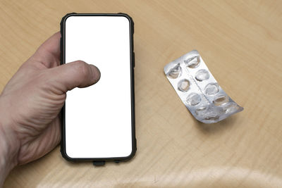 Cropped hand using mobile phone on table