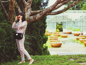 Woman in sunglasses walking on field against tree