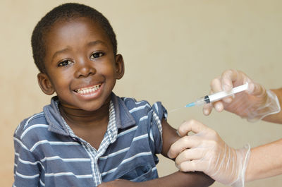 Cropped hands of doctor injecting smiling boy in hospital