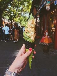 Cropped hand of woman holding ice cream cone in city