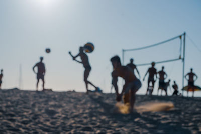 People playing at beach against clear sky