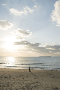 Man standing on beach against sky during sunset