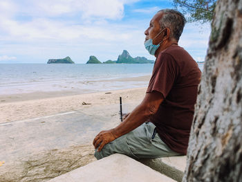 Rear view of man on beach against sky