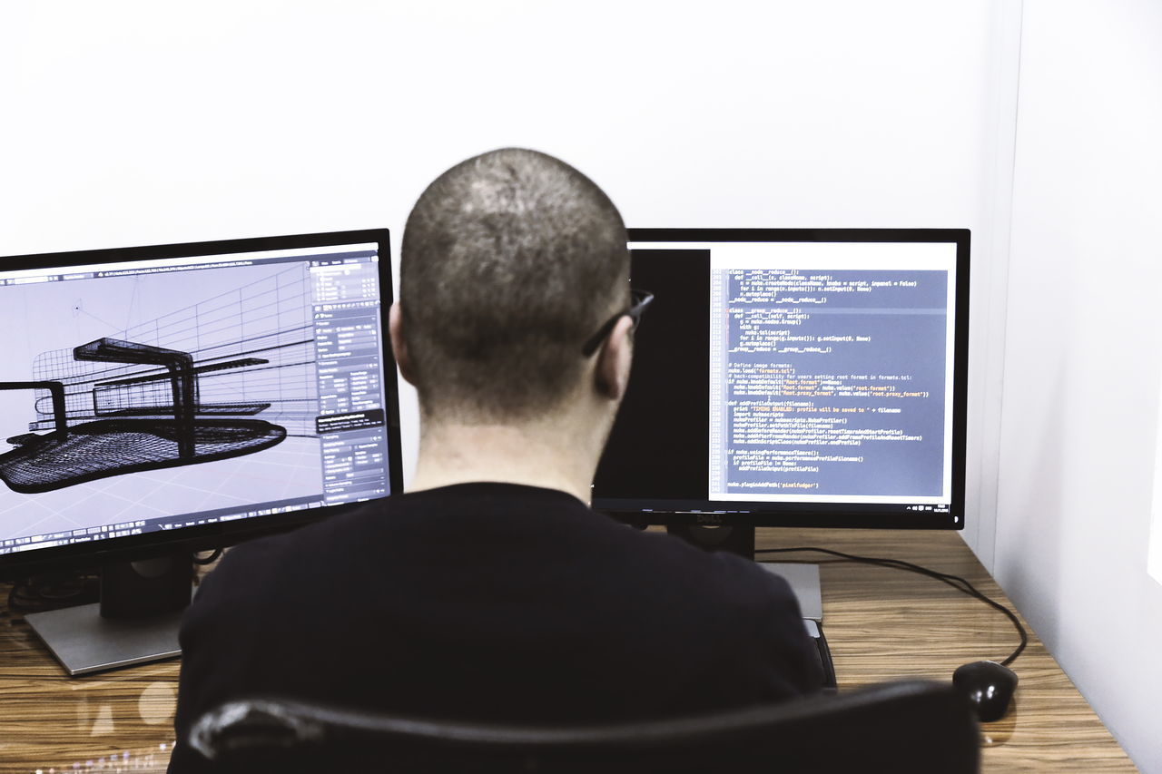 REAR VIEW OF MAN WORKING WITH LAPTOP