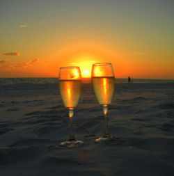 Champagne glasses on beach at sunset