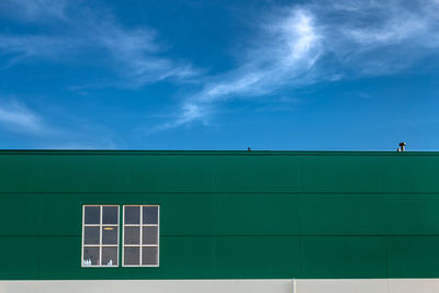 Low angle view of building window against blue sky