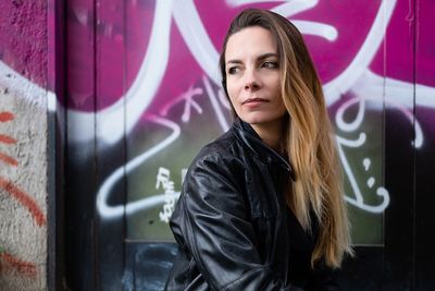 Portrait of woman standing against graffiti wall