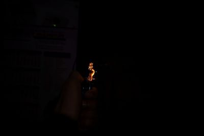 Midsection of man holding cigarette against black background