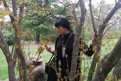 Young woman looking away while standing on tree trunk in forest