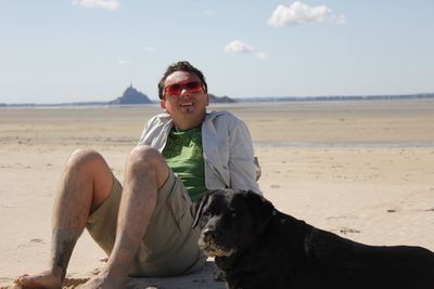 Man with dog sitting on beach