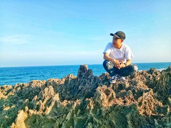 Man sitting in sea against sky