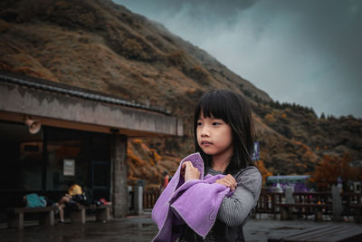 Portrait of young woman standing on mountain against sky