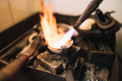 Closeup of burner with flame used for melting metal in small bowl during jewelry creation in professional workshop