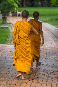 Rear view of boys wearing traditional clothing while walking on footpath