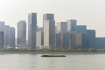 Modern buildings by river against sky in city