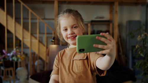 Smiling girl taking selfie at home