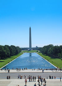 People at monument against clear sky