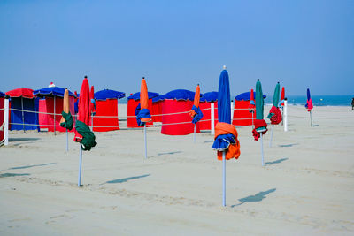 Deck chairs on beach against clear blue sky