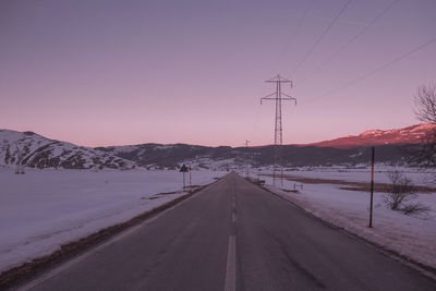 Road by snowcapped mountain against sky during winter