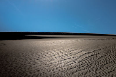 Scenic view of desert against clear blue sky