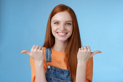 Portrait of a smiling young woman against blue background