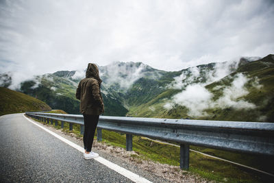 Rear view of woman standing on road by mountains