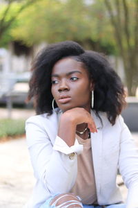 Portrait of young woman looking away while sitting outdoors