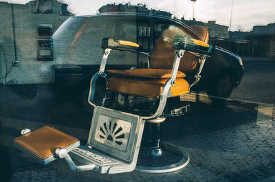 Old-fashioned empty barber chair in salon seen from window glass